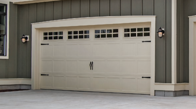 Modern two-story house with black garage doors and wooden siding. White exterior with large windows, green lawn.