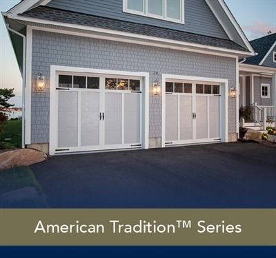 White garage door on a house with stone siding, entry with black door, gray roof.