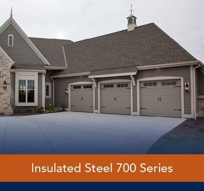 Black garage doors with crisscross design on beige house.
