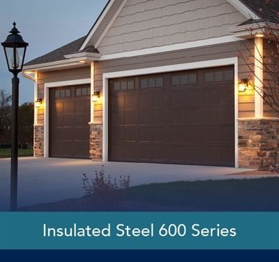 Two-story house with brown garage door and front door; gray siding and stone columns.
