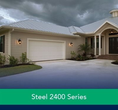 Modern home with two garage doors; tan horizontal panels, black frames; gray exterior.