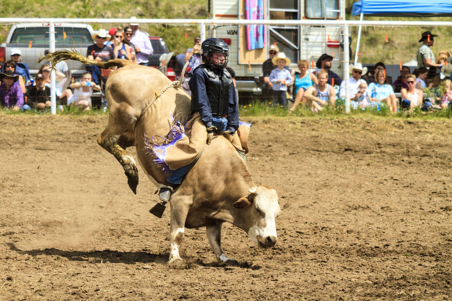 A woman is riding a horse around a barrel at a rodeo.