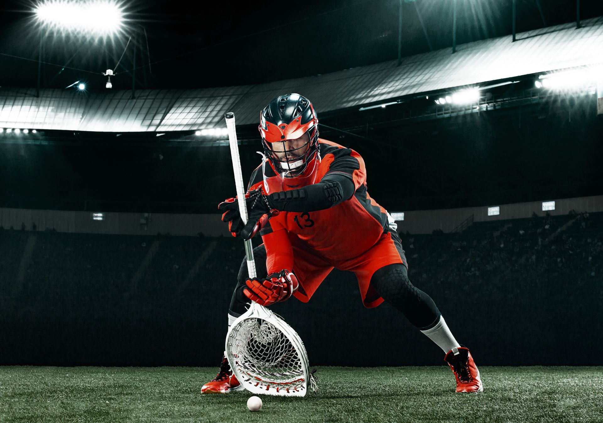 A man is playing lacrosse on a field in a stadium.