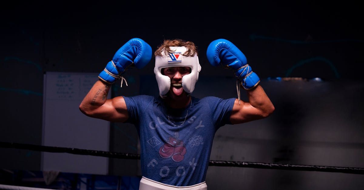 A man wearing boxing gloves and a helmet is standing in a boxing ring.