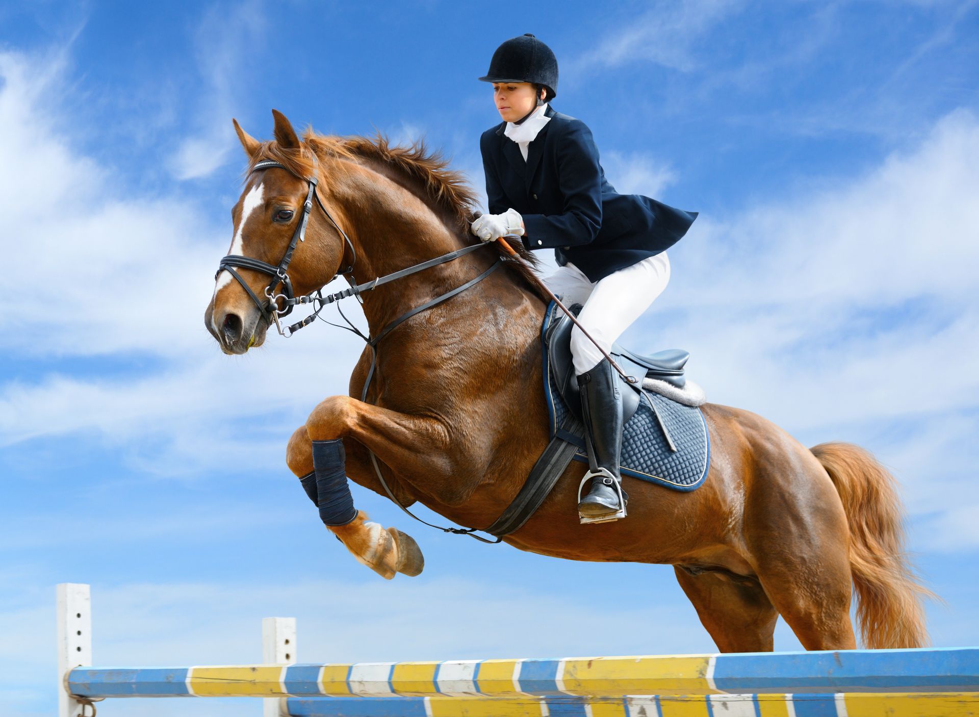 A person is riding a brown horse over a jump.