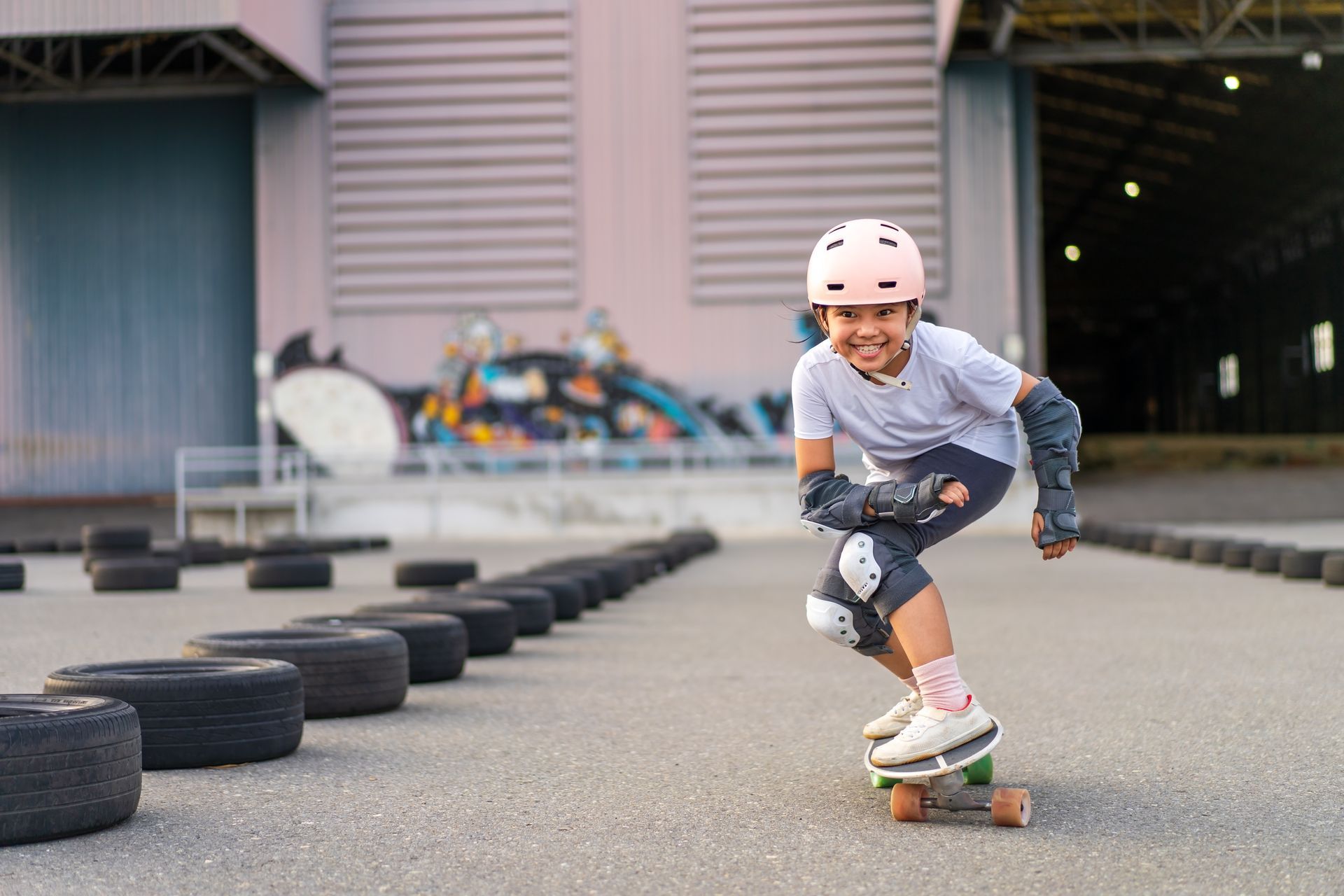A young girl is riding a skateboard on a road.