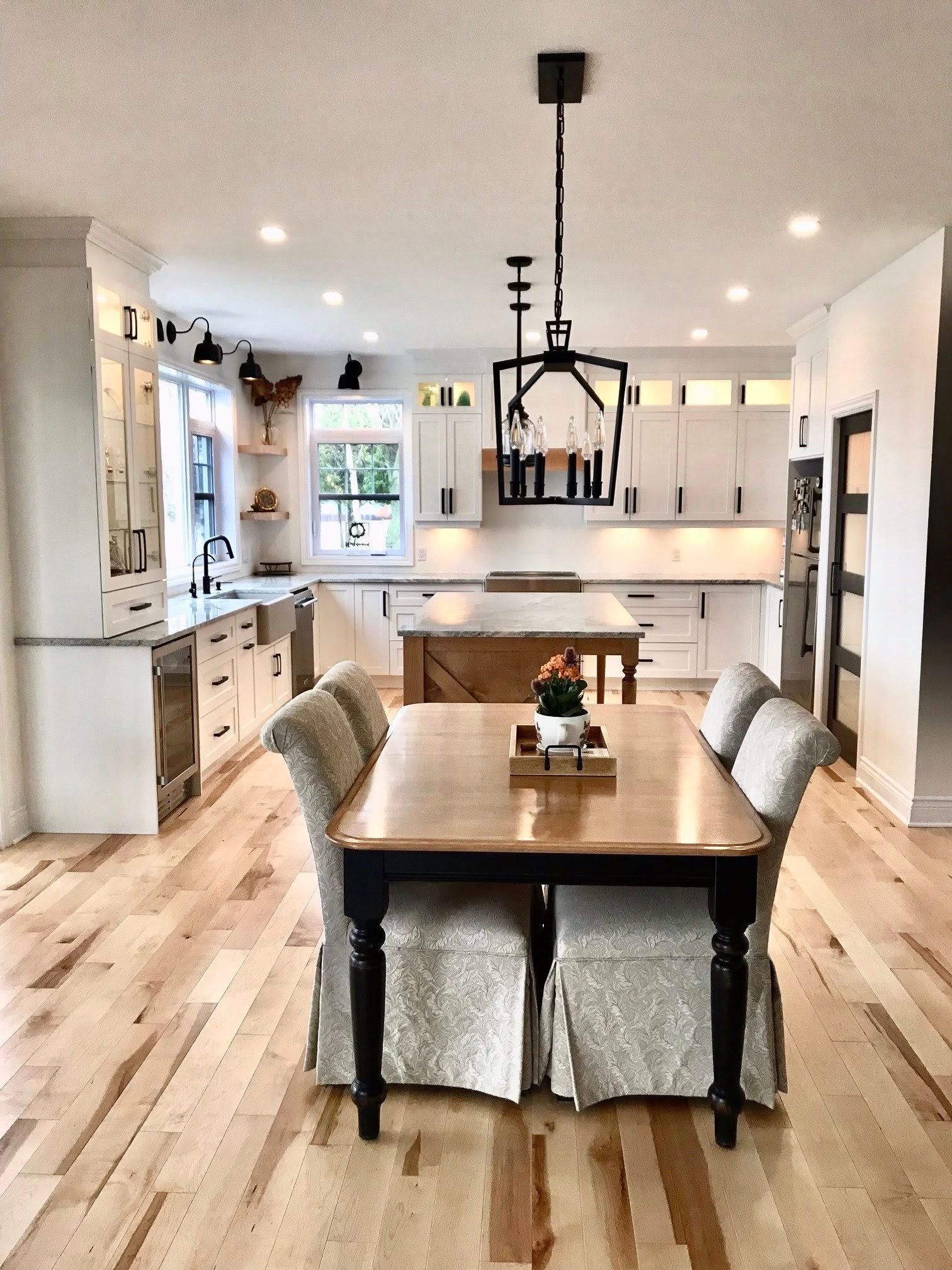 Cuisine moderne avec parquet clair, placards blancs et table à manger avec chaises à jupe.