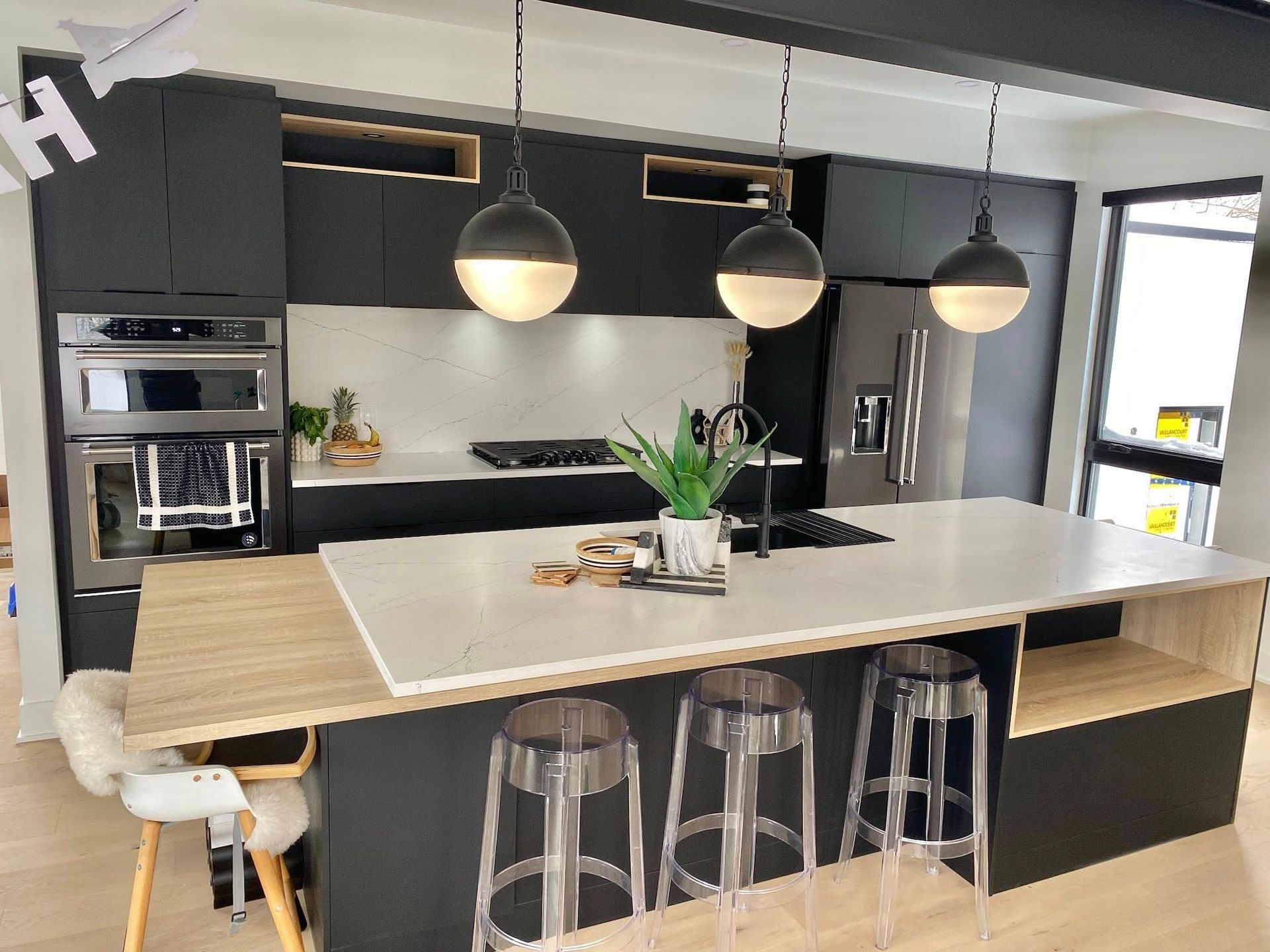 Cuisine moderne en noir et blanc avec îlot central et suspensions lumineuses.