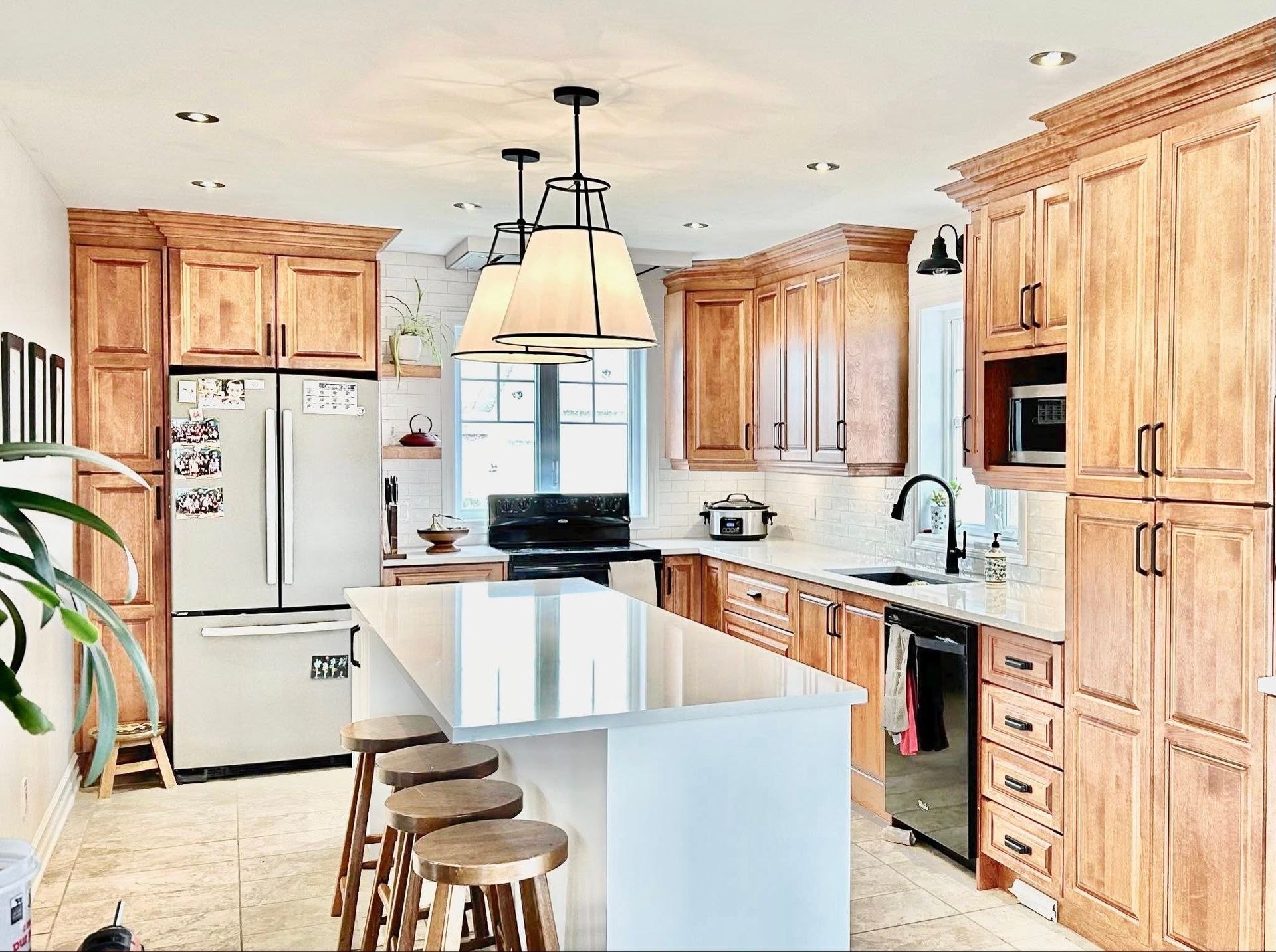 Une cuisine bien éclairée avec des armoires en bois, un îlot blanc et un réfrigérateur.