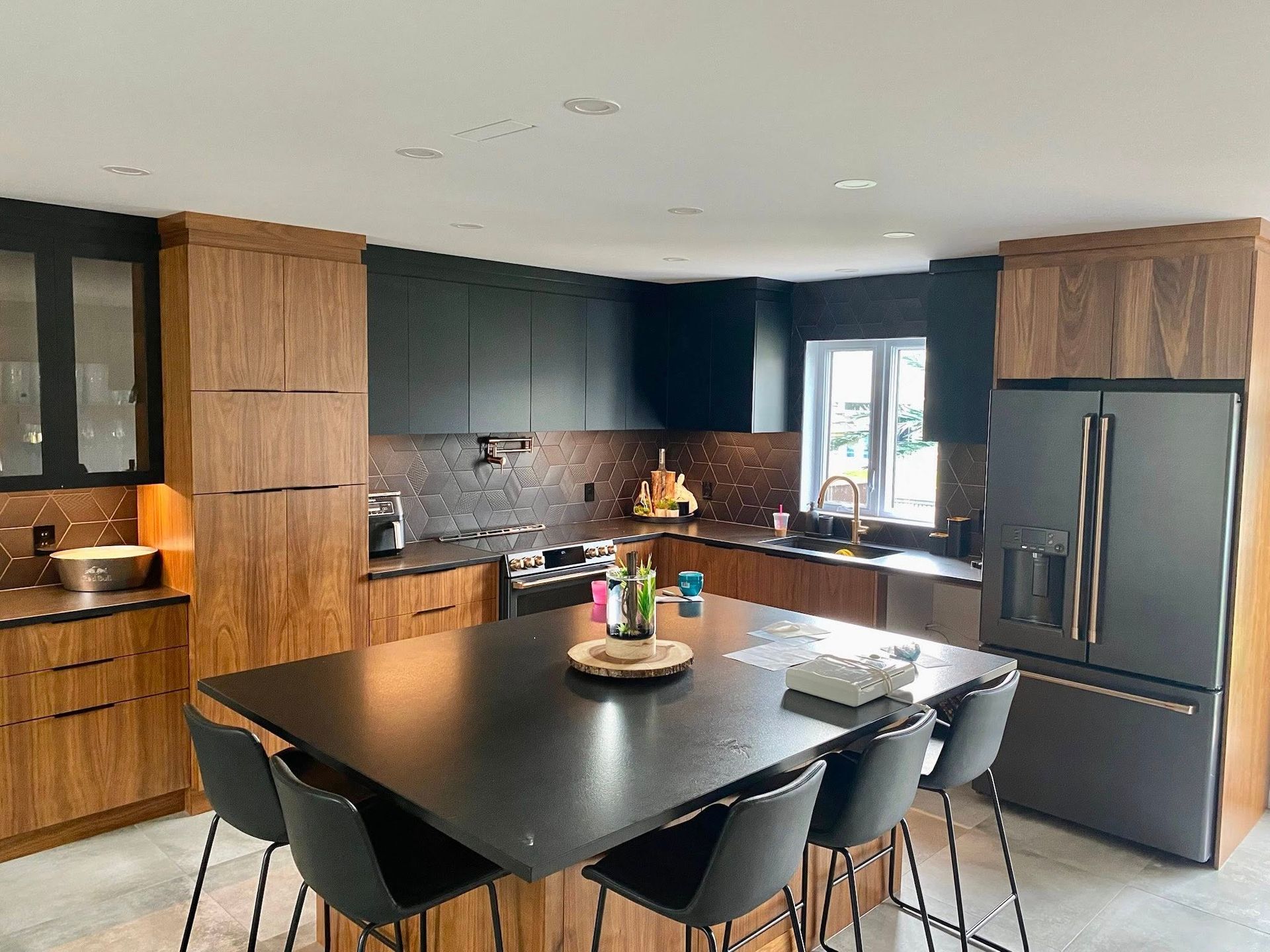 Cuisine moderne avec armoires foncées, îlot noir et éléments en bois.