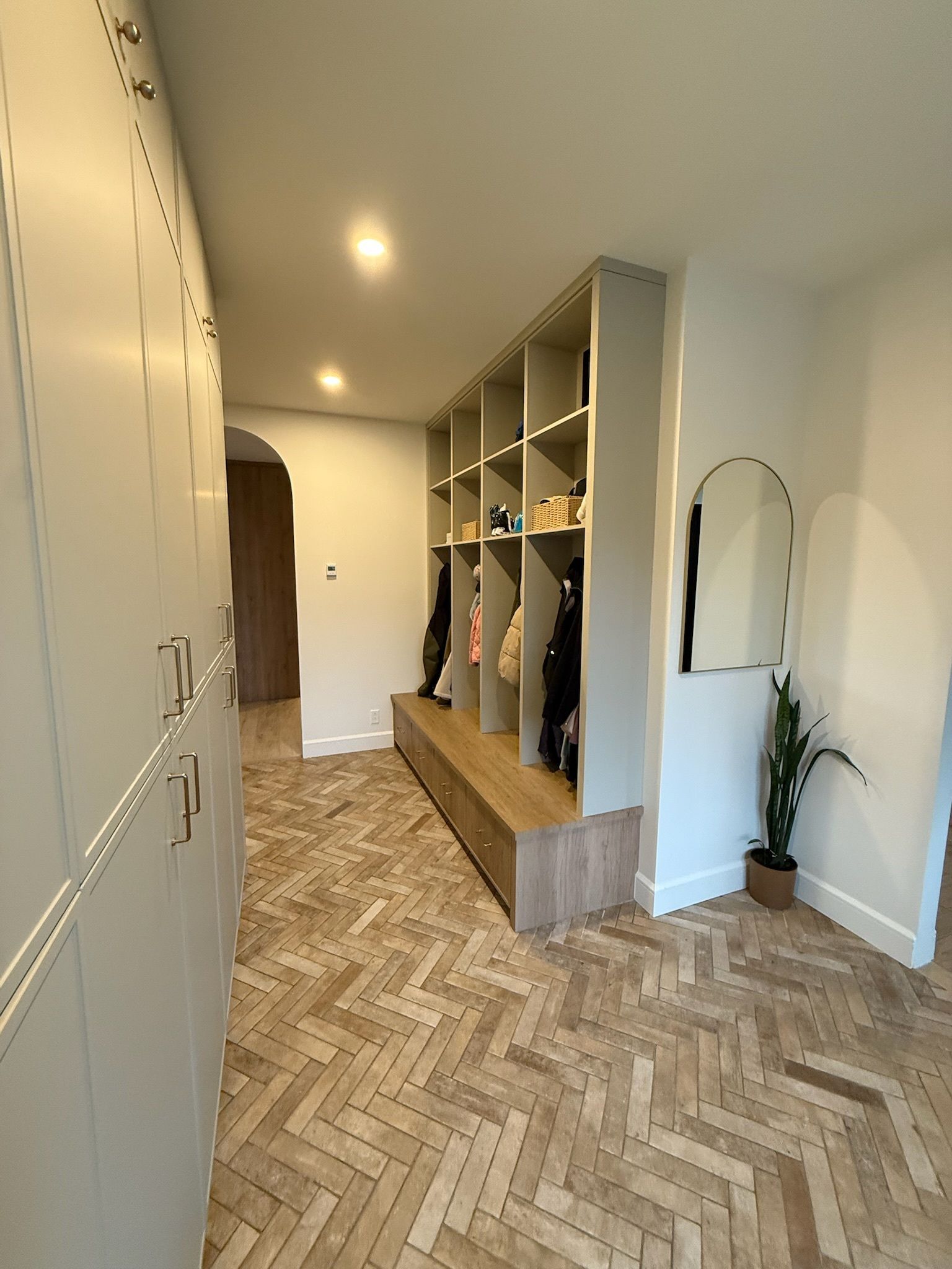 Couloir avec casiers, étagères et banc ; parquet en chevrons.