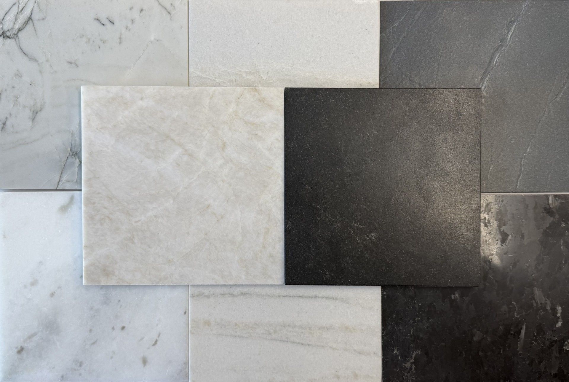 Un assortiment de carreaux de pierre carrés dans des tons de blanc, de gris et de noir.
