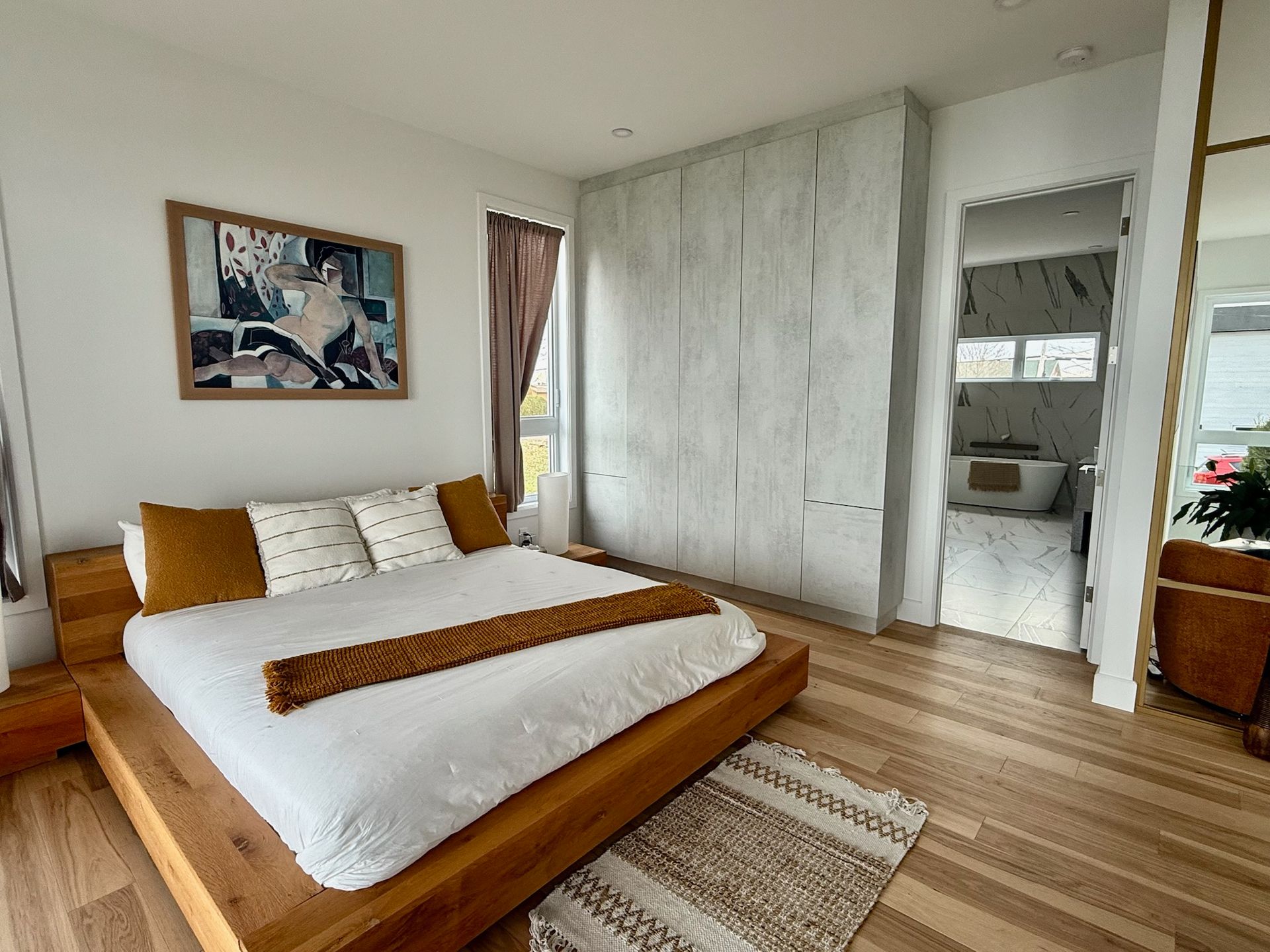 Chambre avec lit plateforme en bois, œuvres d'art, placard intégré et aperçu de la salle de bains.
