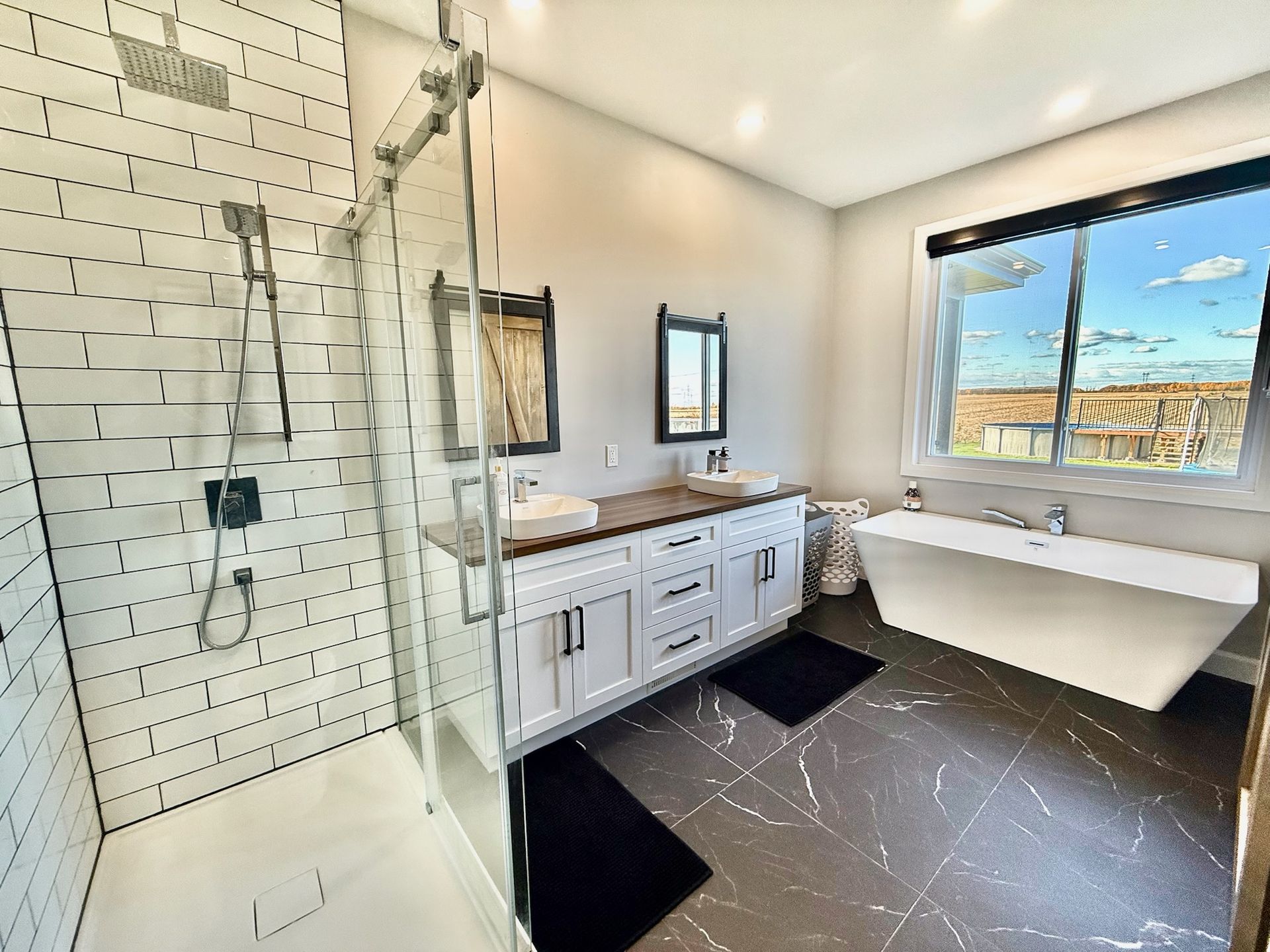 Salle de bains moderne avec douche en carrelage métro blanc, double vasque et baignoire îlot.