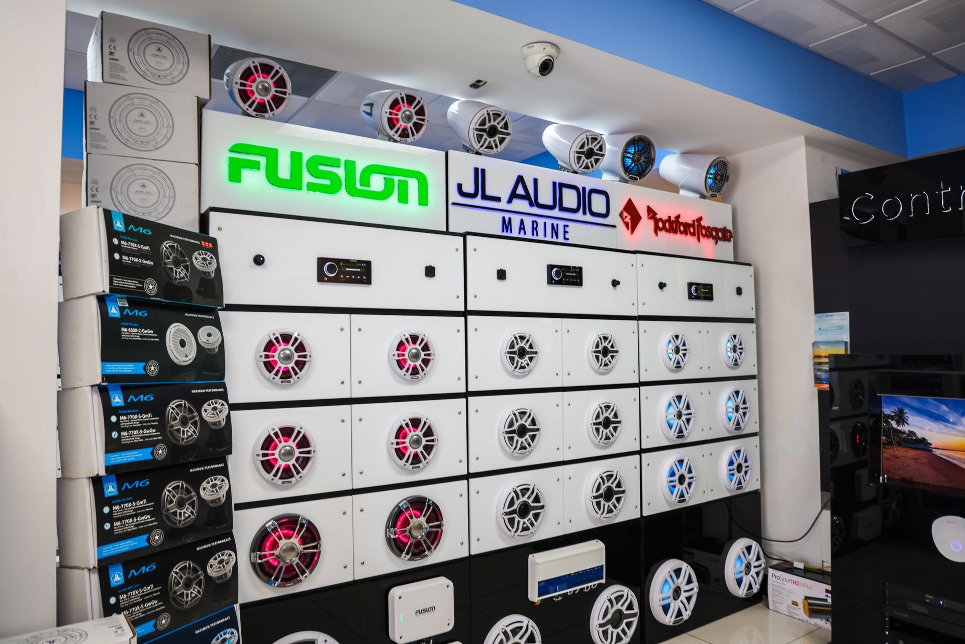 A wall filled with lots of speakers and a sign that says fusion jl audio