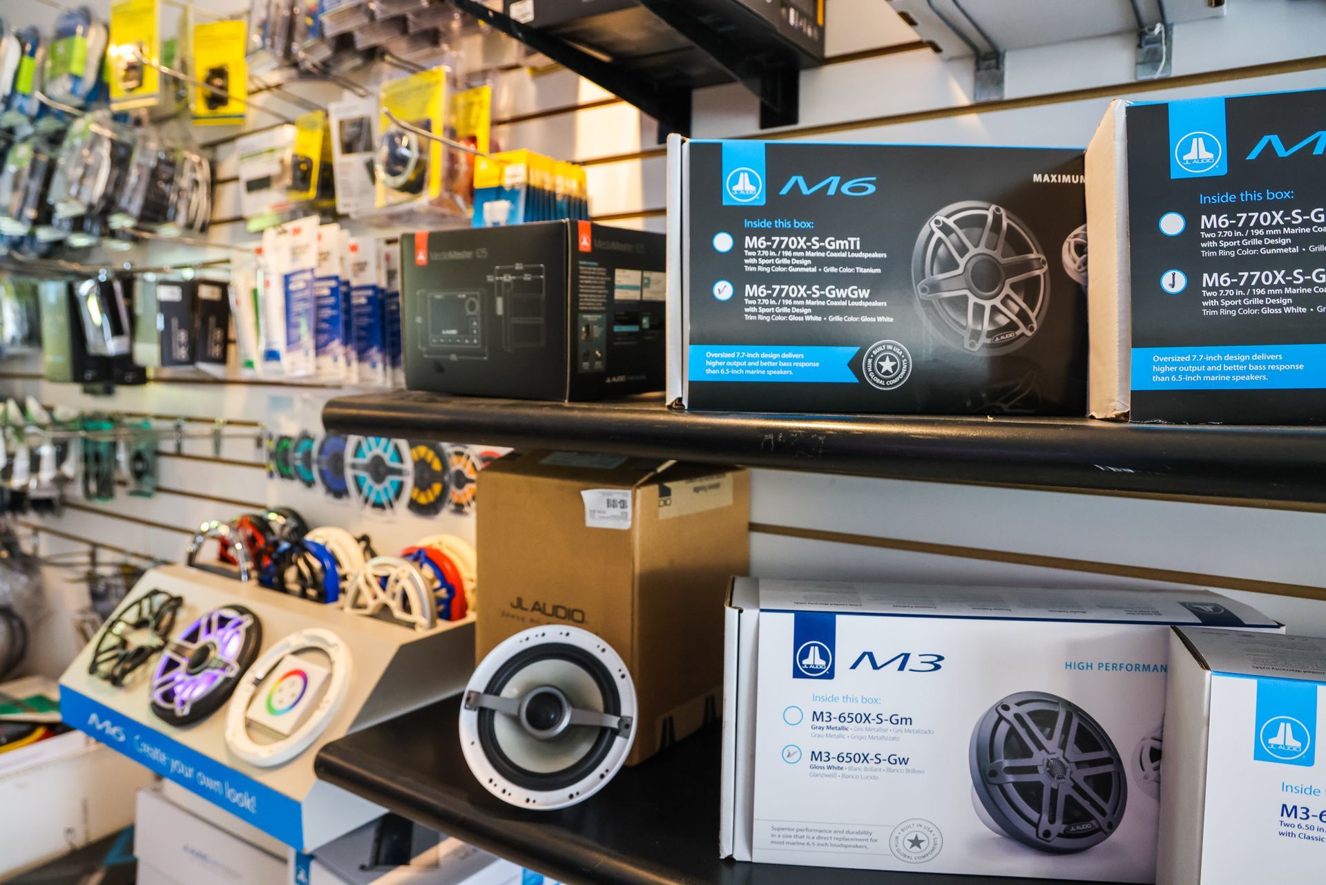 A bunch of speakers are sitting on a shelf in a store.