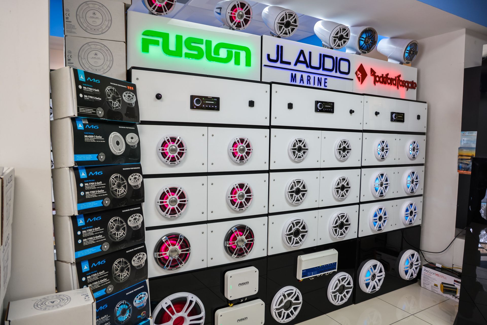 A wall filled with speakers and a sign that says fusion jl audio