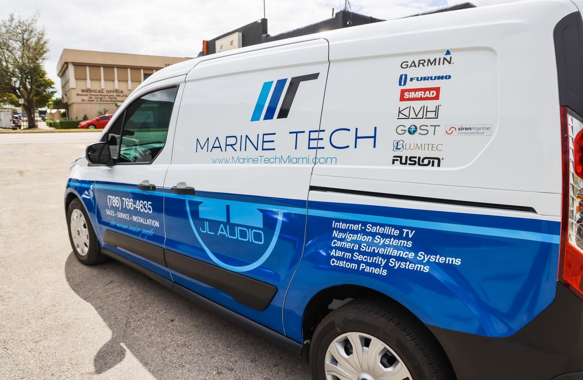 A blue and white van with marine tech written on the side is parked in a parking lot.