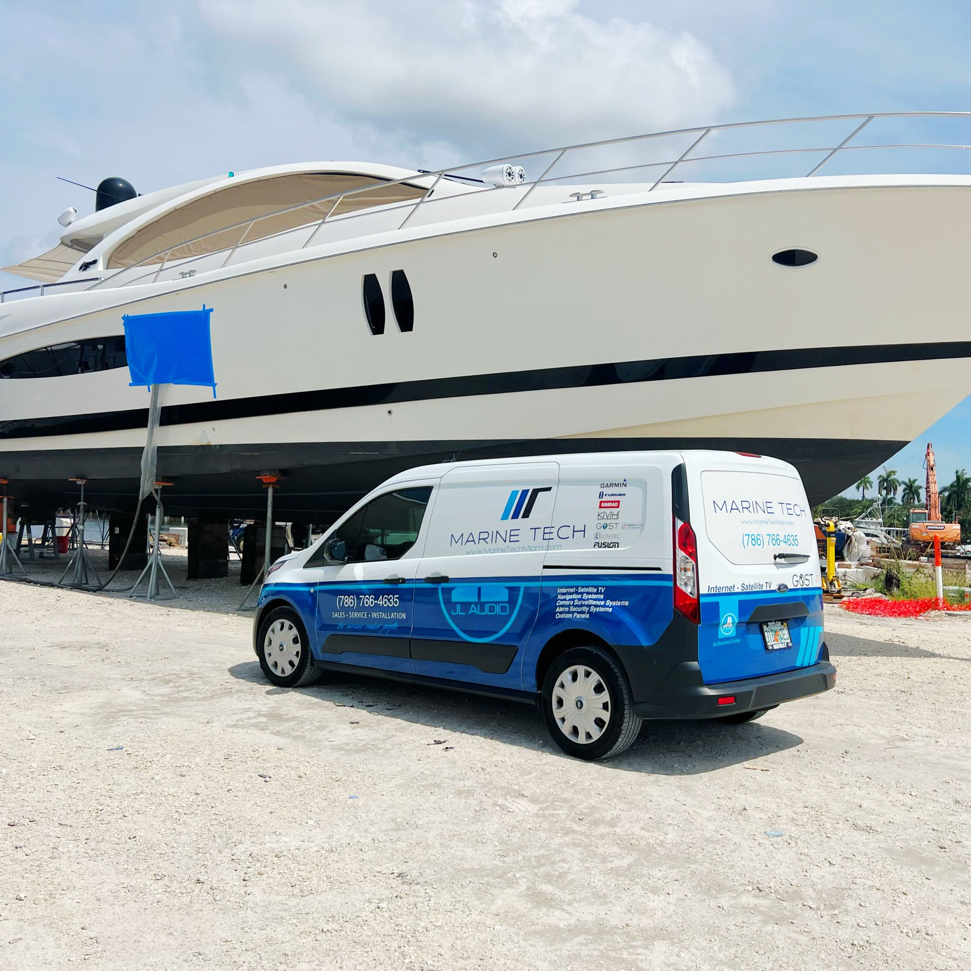 A blue and white van is parked in front of a large boat
