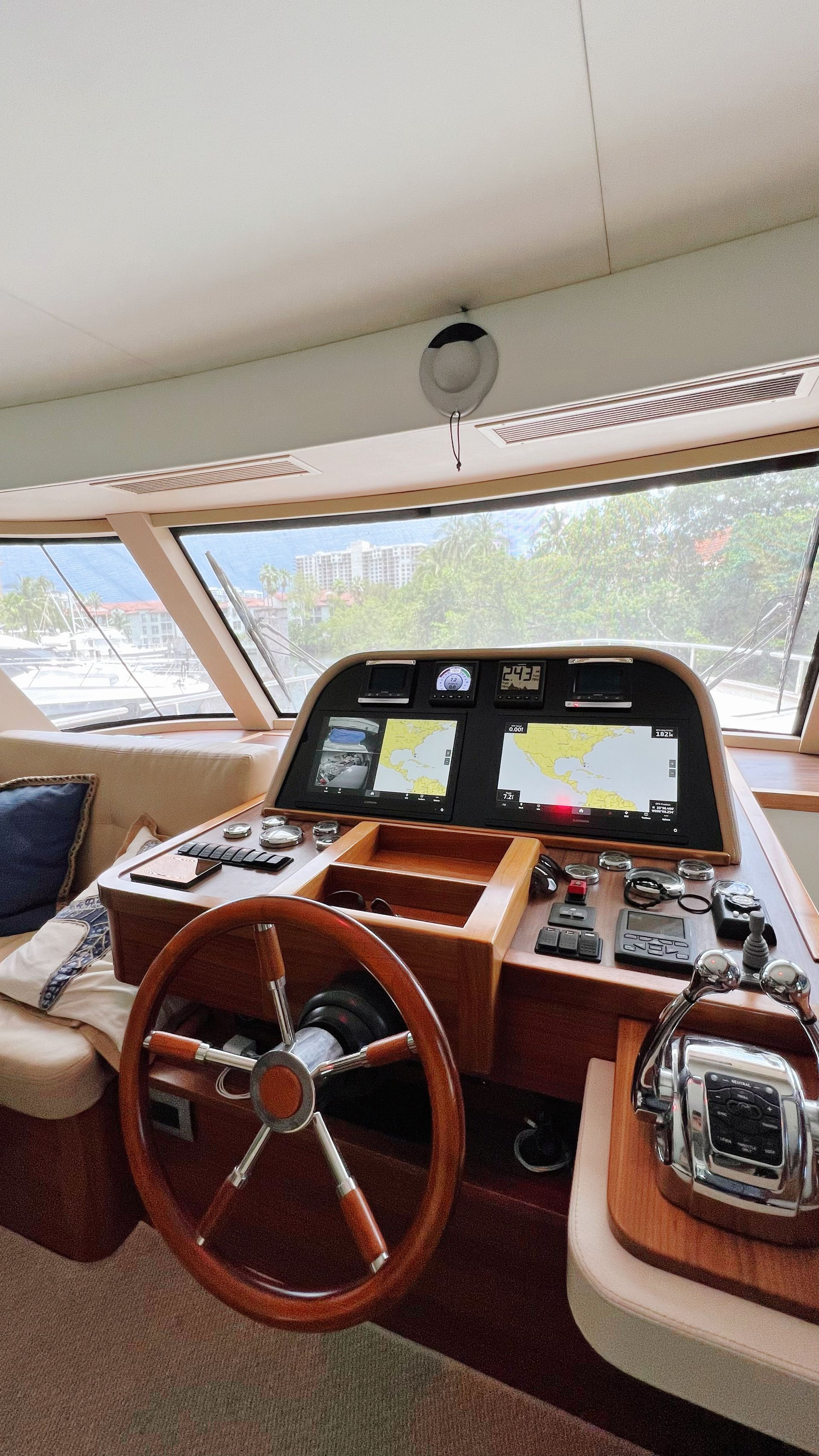 A wooden steering wheel is in the cockpit of a boat.