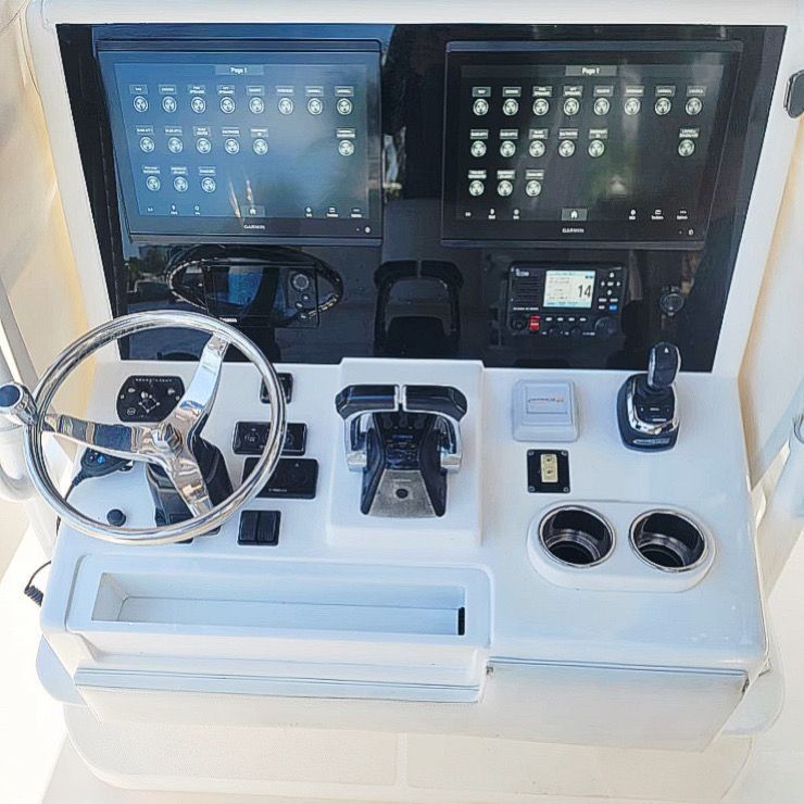 A boat control panel with a steering wheel and a monitor