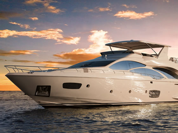 Luxury white yacht cruising on calm water at sunset with orange clouds in the sky