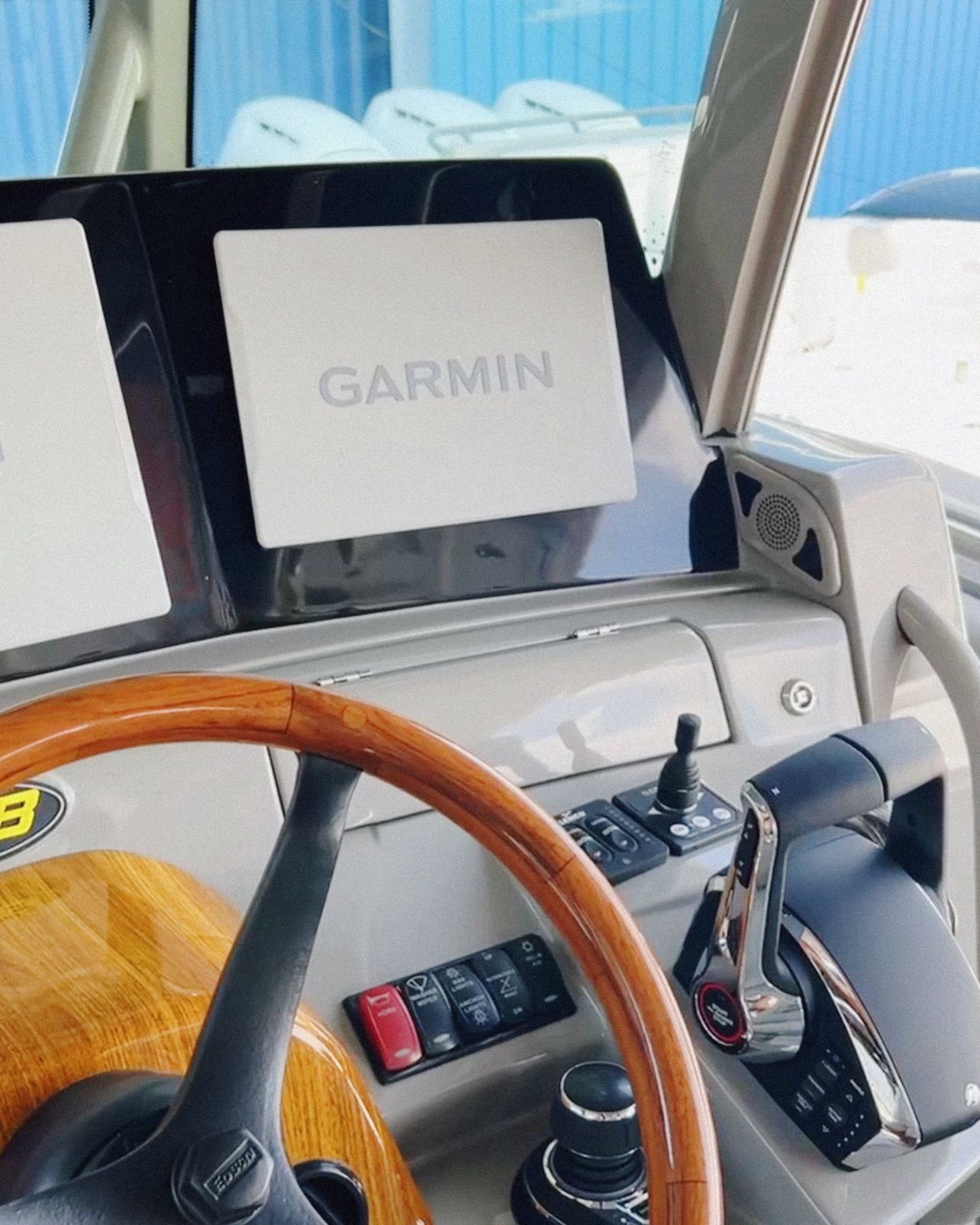 A steering wheel and dashboard of a boat with a garmin monitor