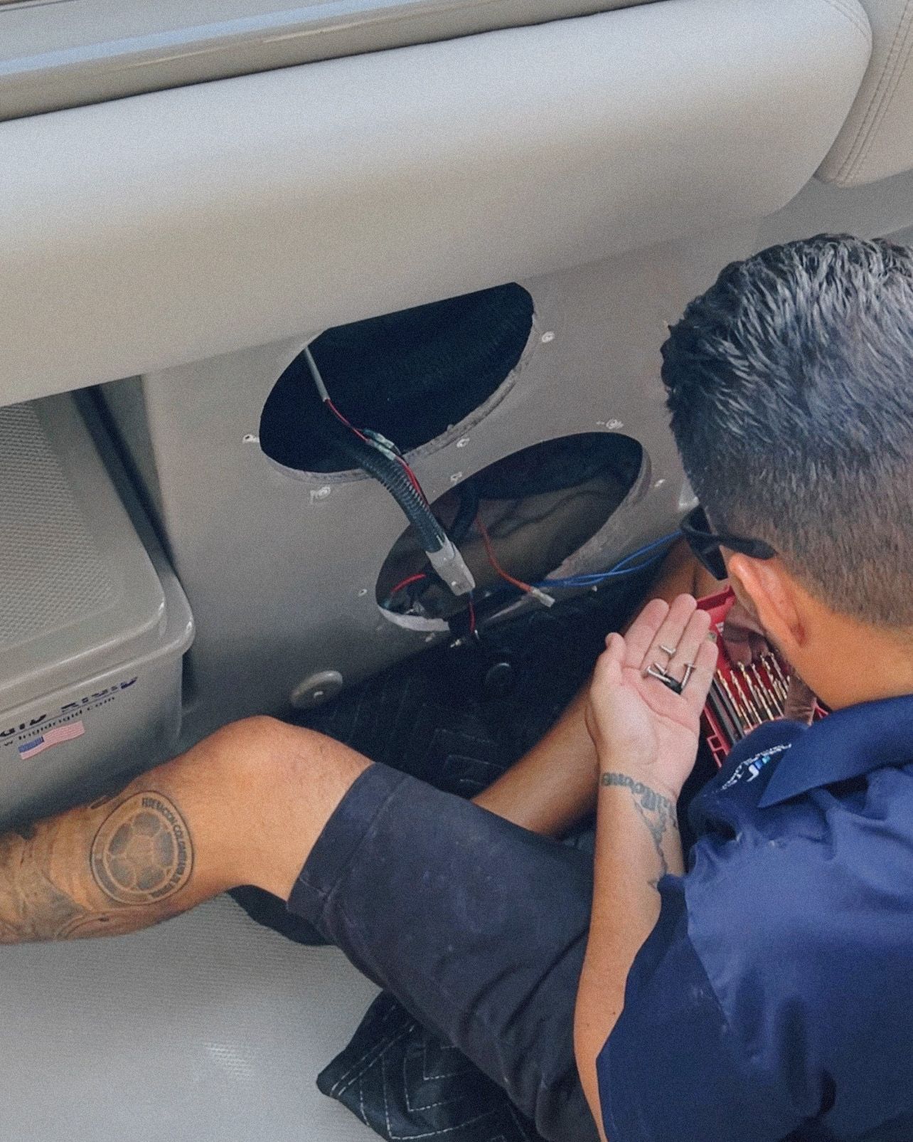 A man with a tattoo on his leg is working on a boat