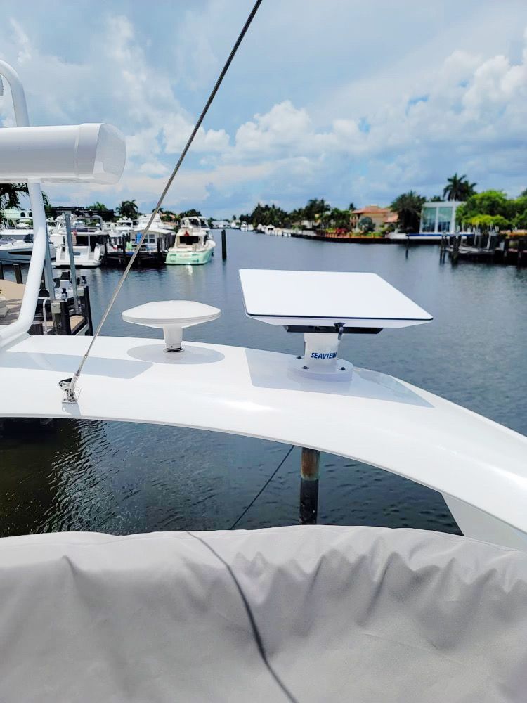 A white boat is docked in a marina with boats in the background