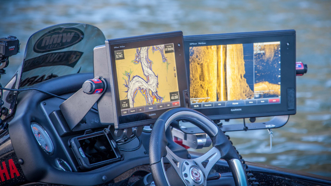 Dashboard of a boat with two large screens displaying lake maps and sonar readings.