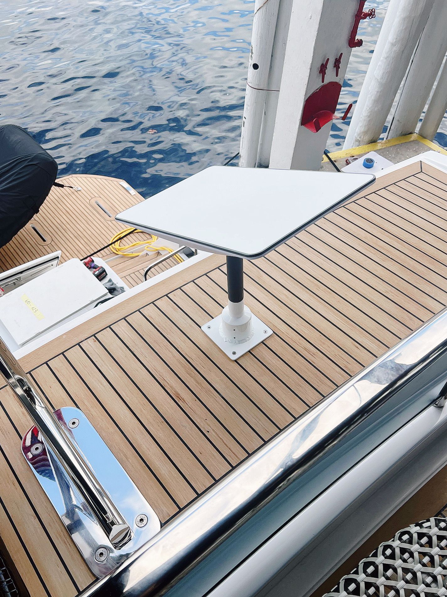 A white table is sitting on top of a wooden deck on a boat.