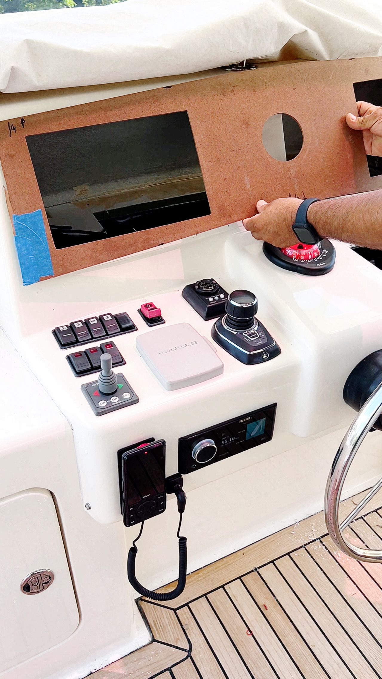 A person is sitting at the steering wheel of a boat.