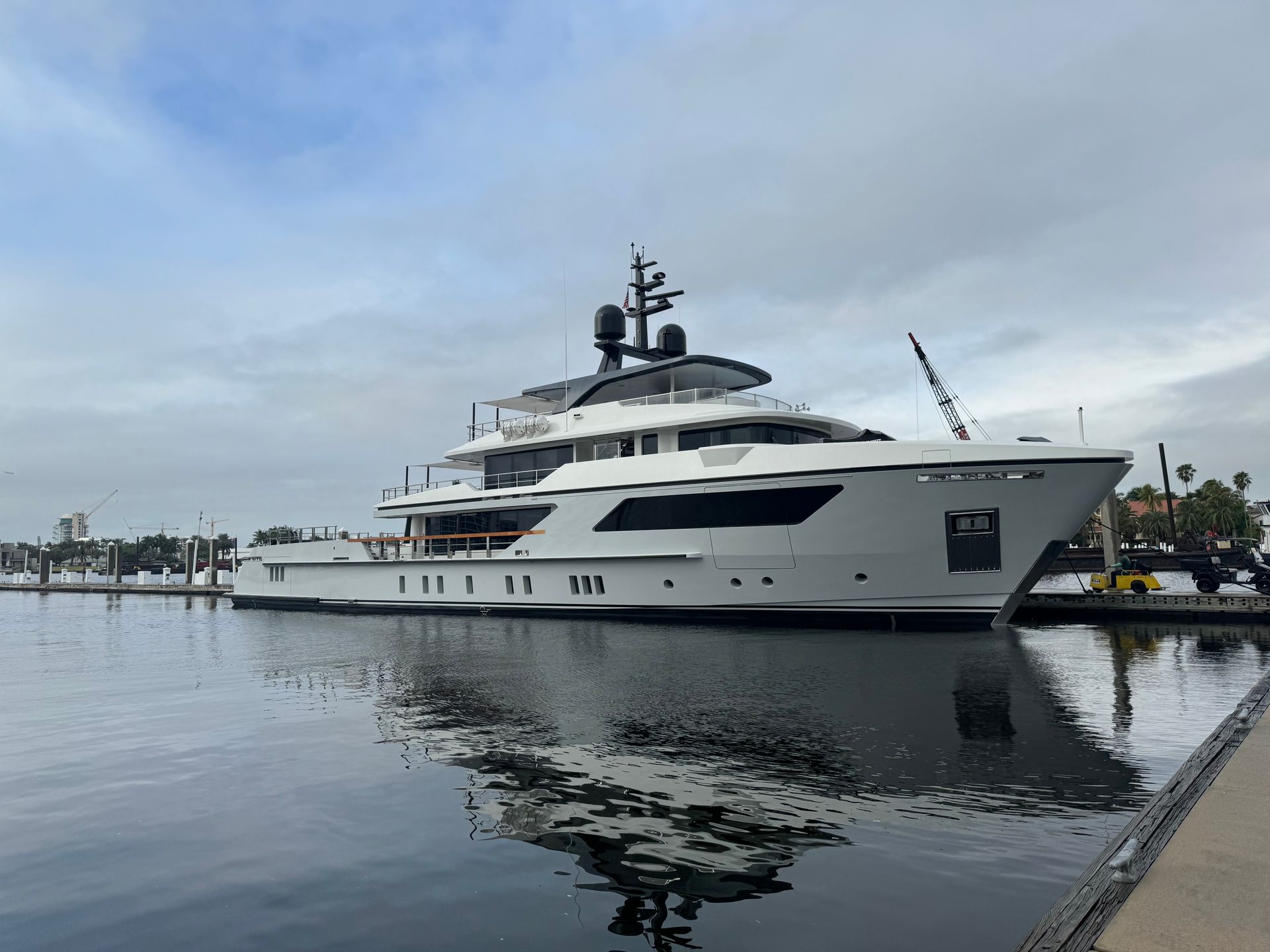 A large white yacht is docked in a harbor.