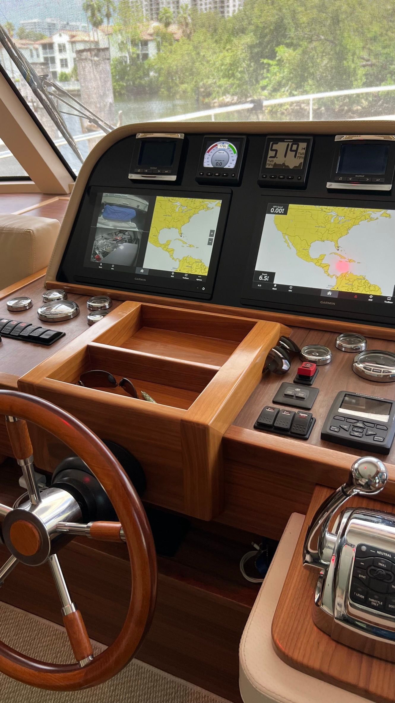 The cockpit of a boat with a wooden steering wheel and dashboard.