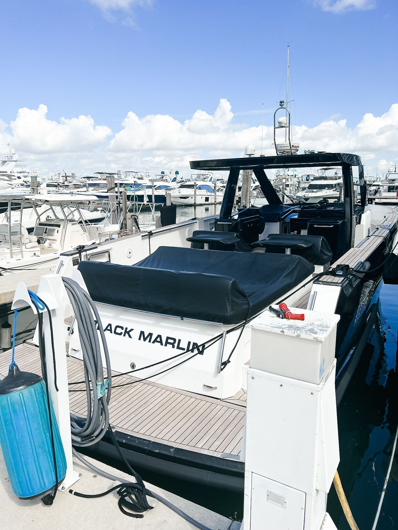 A black marlin boat is docked at a marina