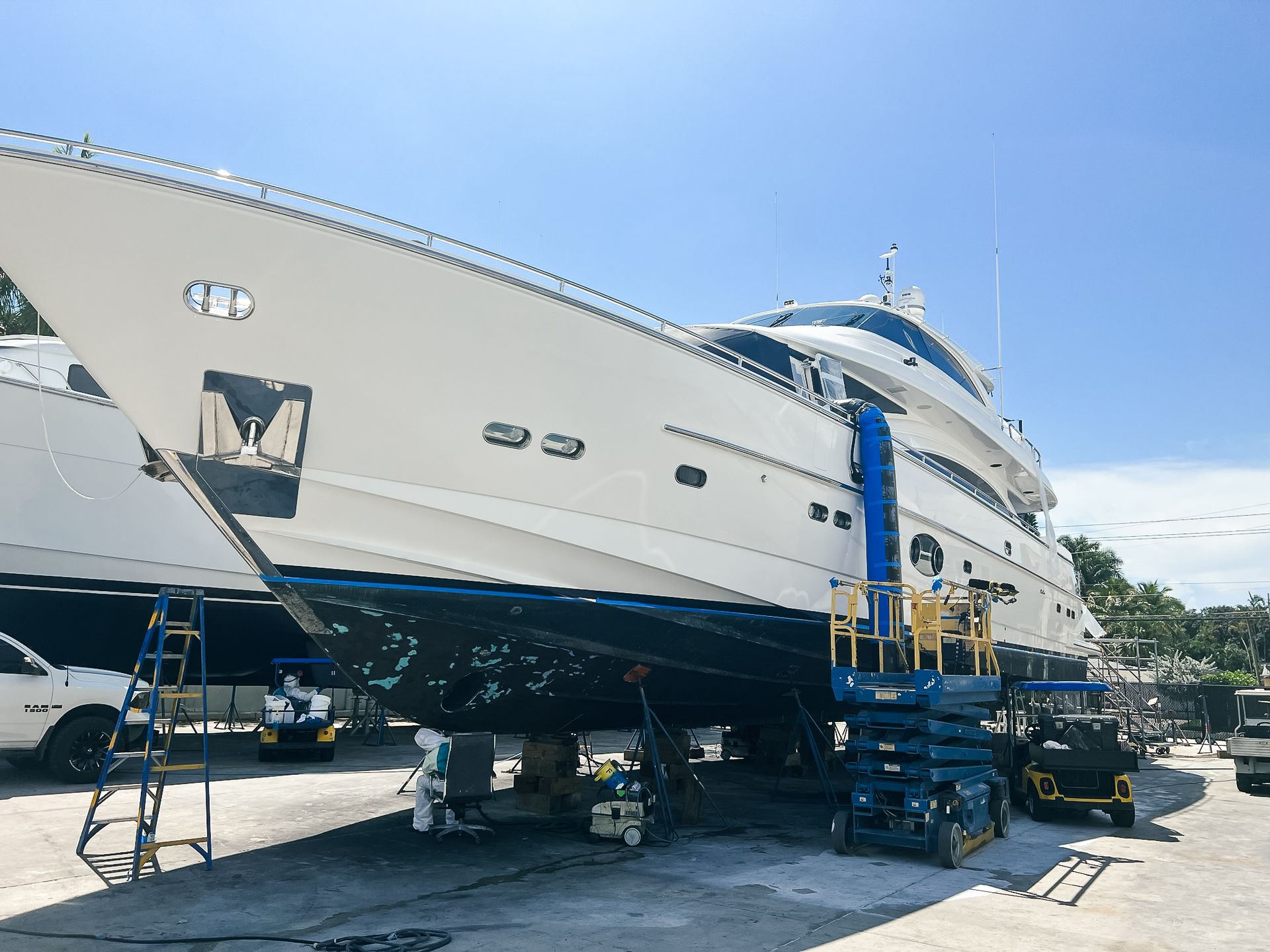 A large white yacht is being worked on in a marina.