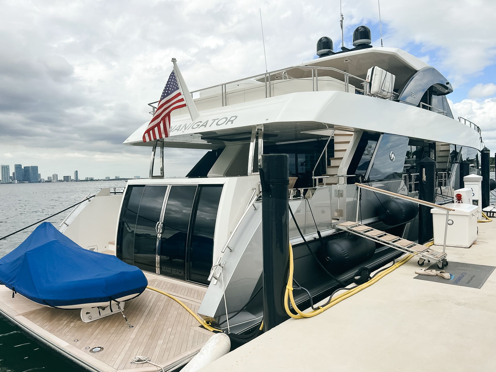 A large yacht is docked at a dock with a jet ski on the deck.