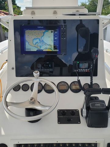 The front of a boat with a steering wheel and a monitor.