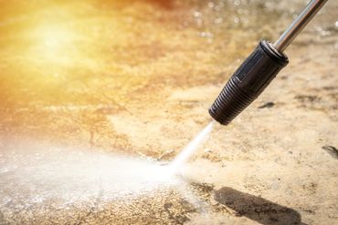 A person is using a high pressure washer to clean a concrete surface.