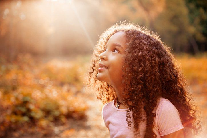 Afro American cute little girl with curly hair looking up at sun rays from the sky - Child, Praying, Praising - Religion, Smiling, Girl, Fixing Our Eyes Upon Jesus