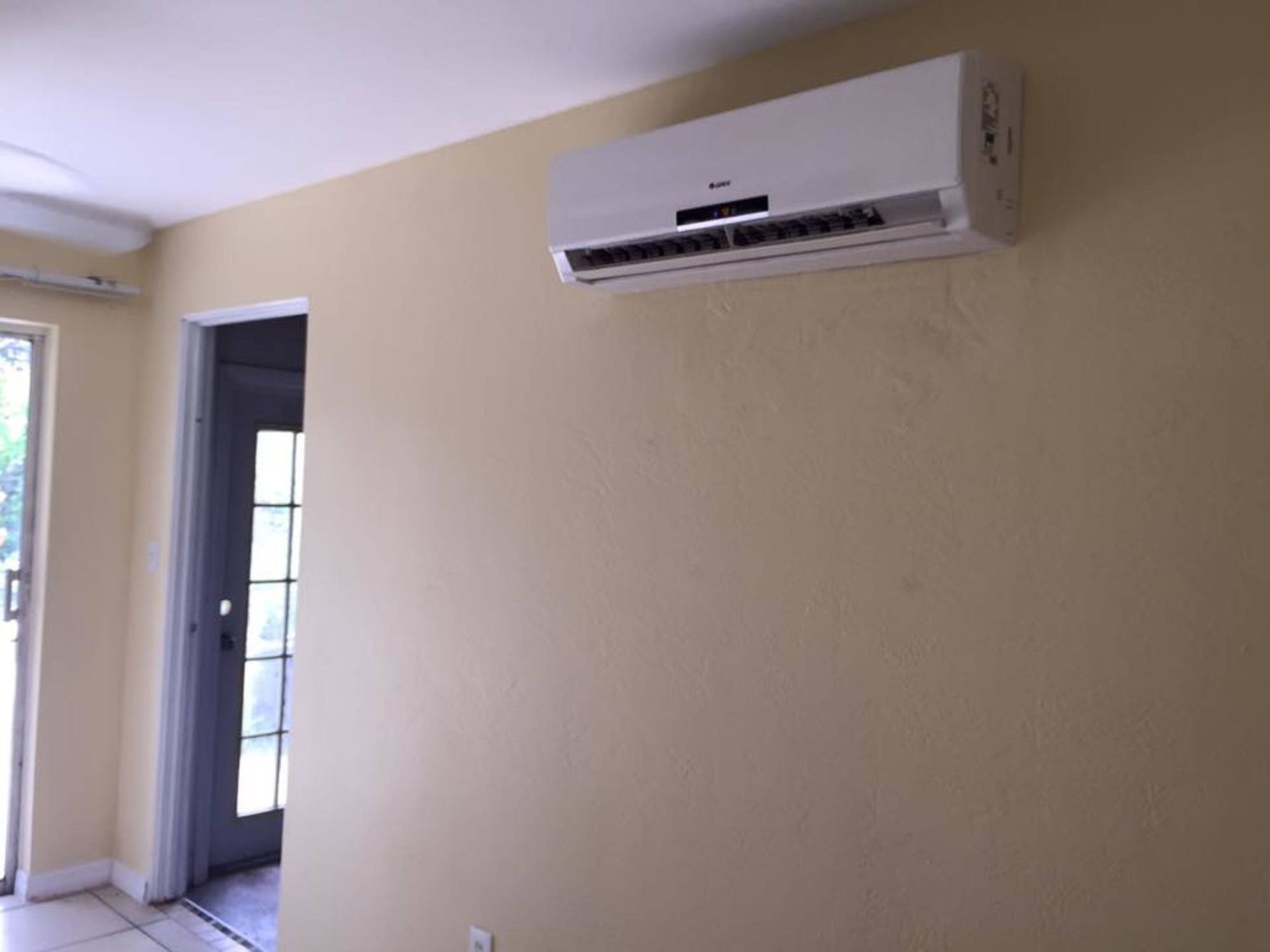 A room with a sliding glass door and a wall mounted air conditioner.