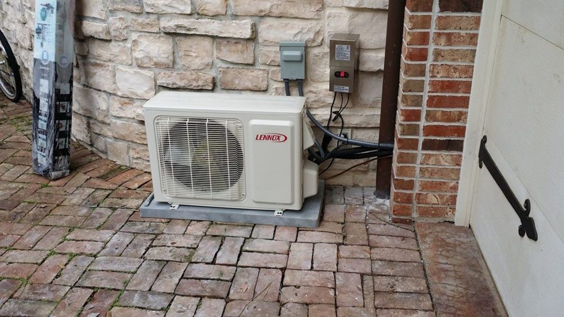 A man in a blue hat is cleaning an air conditioner.