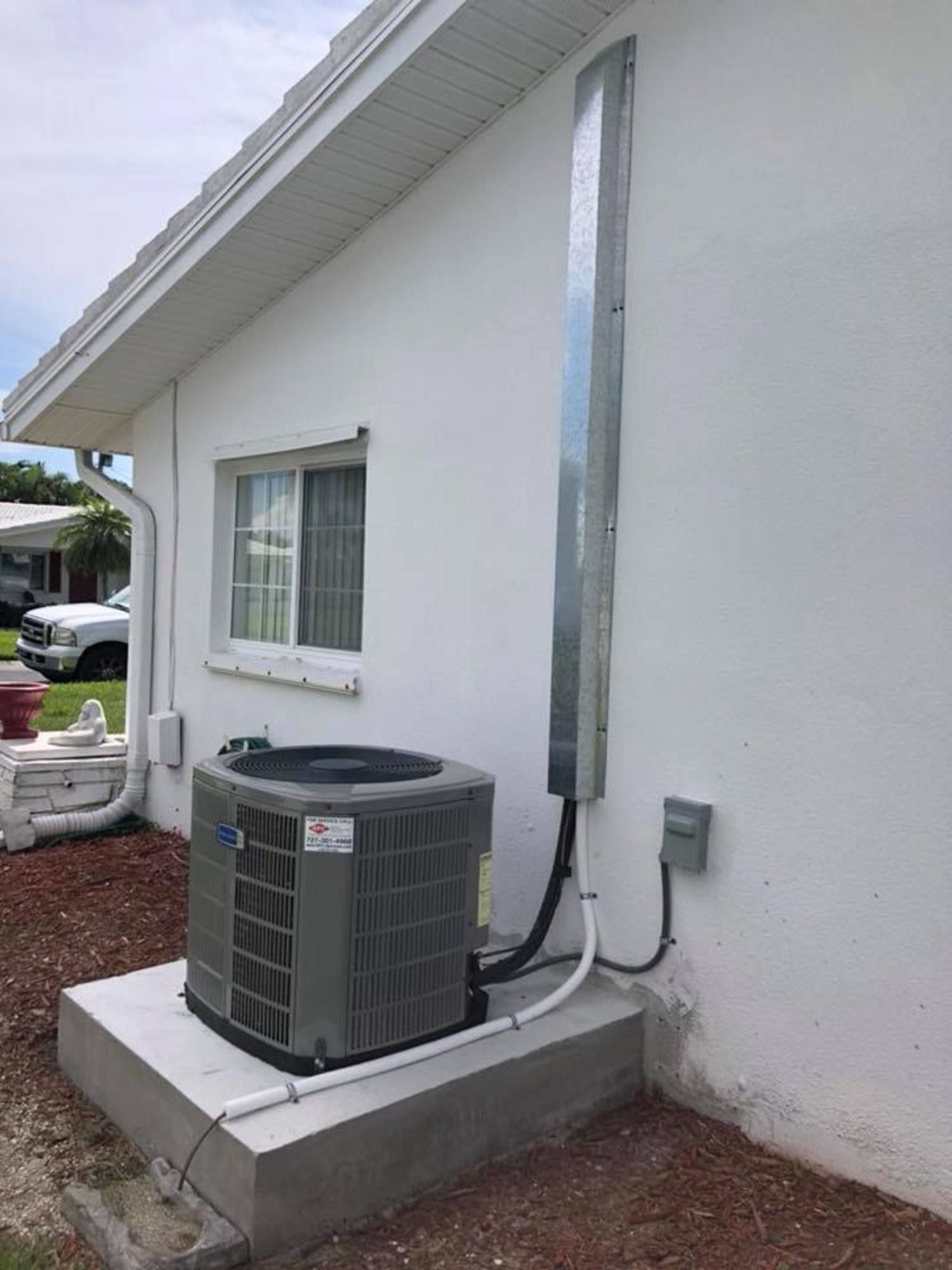An air conditioner is installed on the side of a white house.