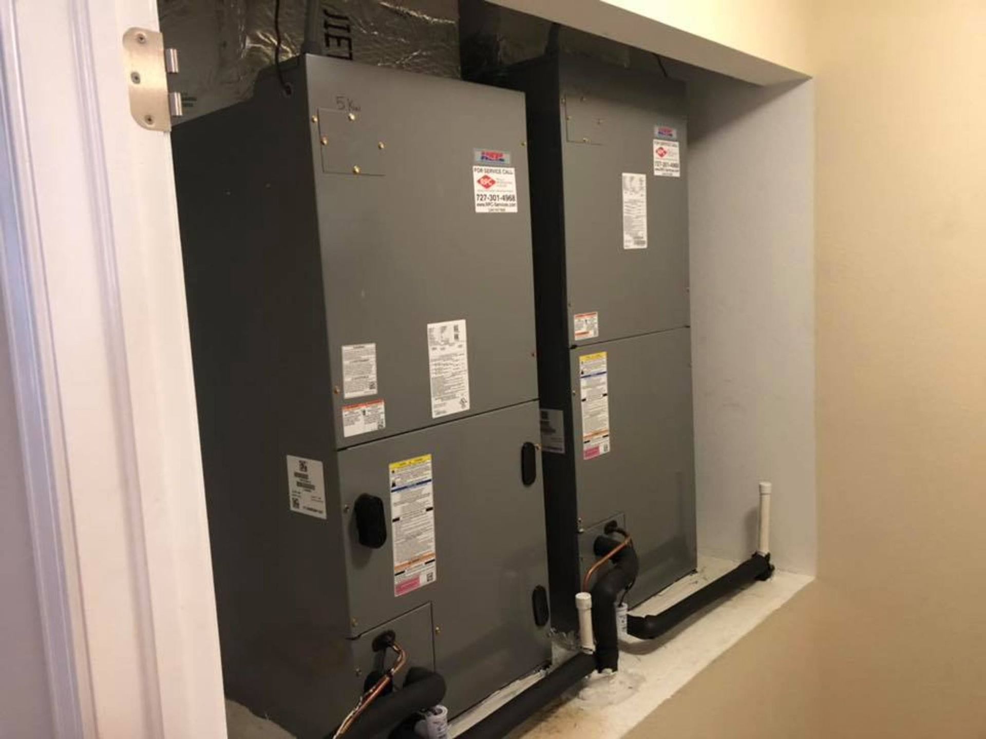 Two air conditioners are sitting in a corner of a room.