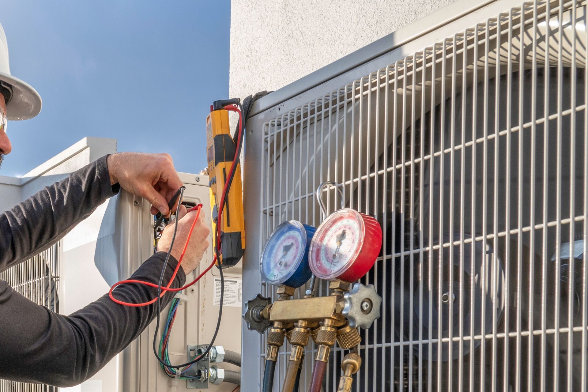 A man is working on an air conditioner outside of a building.