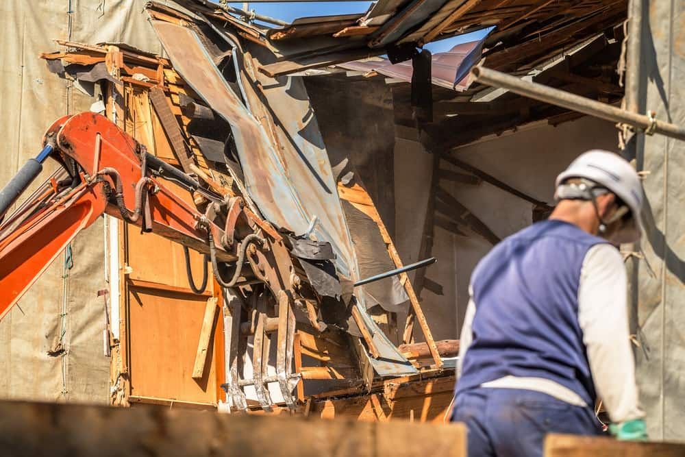 A Man Is Standing in Front of A Building that Is Being Demolished — Barry's Recycling in Redland Bay, QLD