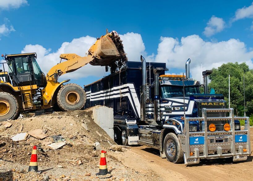 A Construction Worker Is Holding a Piece of Wood in Front of A Building Under Construction — Barry's Recycling in Redland Bay, QLD