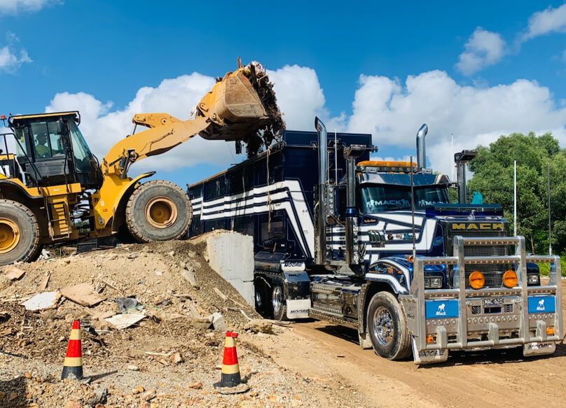 A Dump Truck Is Being Loaded with Dirt by A Bulldozer — Barry's Recycling in Redland Bay, QLD