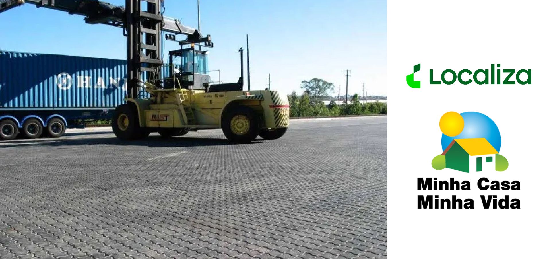 A forklift is carrying a container on a road next to a minha casa minha vida logo