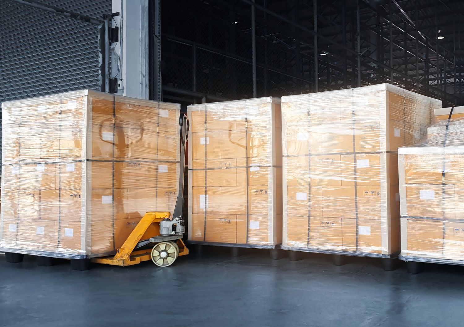 Pallet jack lifting a stack of large wooden crates at a loading dock.